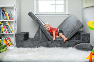 Toddler engaged in screen‑free play on a modular kids couch in the living room.