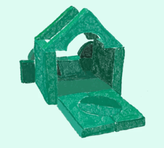 A green plastic dog toy house with a slanted front door and a circular opening on the base, shown against a light mint green background.