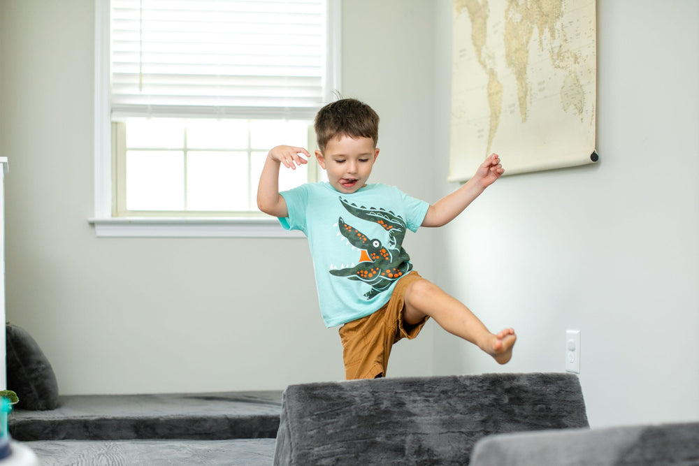 Boy jumping over a dark grey FoamOh modular kids couch